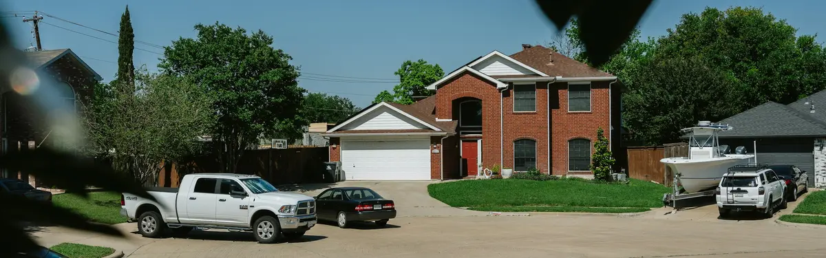 Brick house with cars in the driveway.