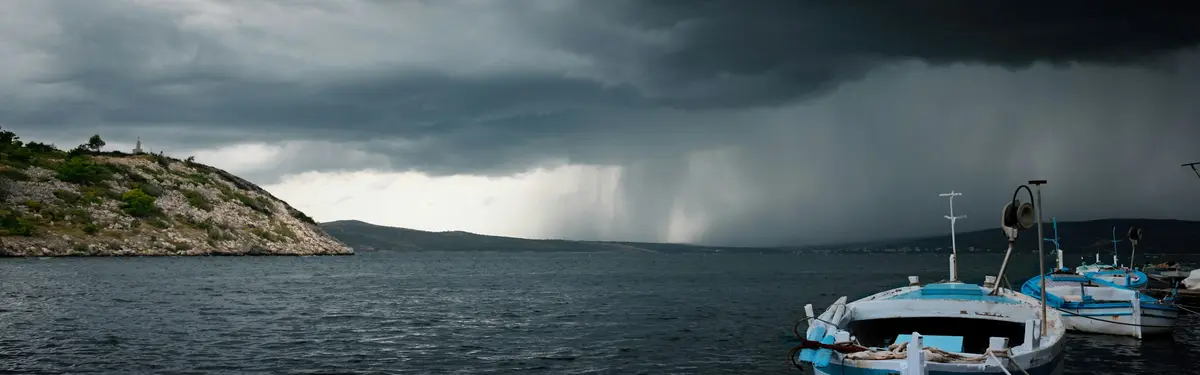 black storm clouds over boats moored at beach
