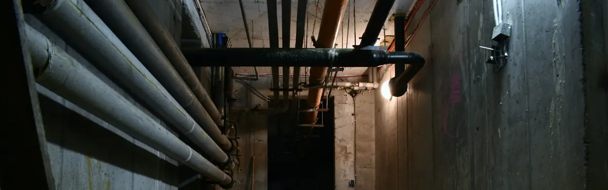 a dark room with pipes and a sheet of paper on the floor